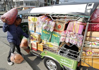A Thai driver loads consumer goods onto a three wheeled motorized auto rickshaw taxi or Tuk Tuk in Bangkok, Thailand, 3 June 2013. (Photo: AAP)