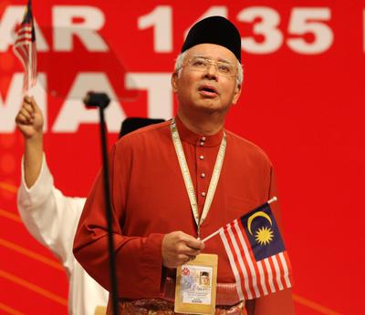 Malaysian Prime Minister Najib Abdul Razak holds the national flag during the opening ceremony of the UMNO 67th General Assembly in Kuala Lumpur, 5 December 2013. (Photo: AAP)