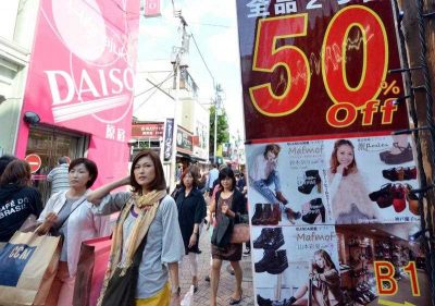 This photograph taken on 27 September 2013 shows shoppers walking past displays offering clothing on sale in Tokyo's Harajuku shopping district. (Photo: AAP)