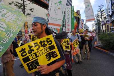 A demonstrator holds a sign against the new legislation that would allow the military to deploy overseas, in Tokyo outside of Japan's parliament against new legislation on September 23, 2015 (Photo: AAP)