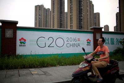 A man rides an electronic bike past a billboard for the upcoming G20 summit in Hangzhou, China.
