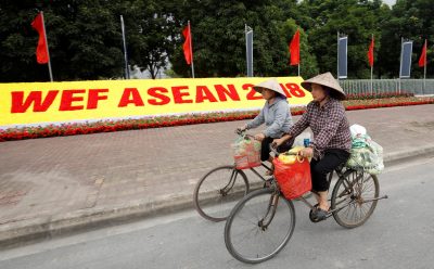 Vietnamese women ride bicycles past the National Convention Center, the venue for World Economic Forum on ASEAN in Hanoi, Vietnam, 11 September 2018 (Photo: Reuters/Kham).
