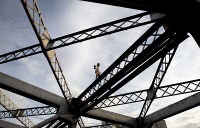 A boy walks on one of the trusses of the Quezon Bridge in Manila. (Photo: AAP).