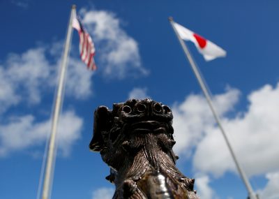 The US and Japanese national flags are hoisted next to a traditional Okinawan Shisa statue at the US Marine’s Camp Foster in Ginowan, on the southern island of Okinawa, Japan, 18 June 2016. (Photo: Reuters/Jim Kelly).