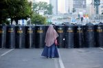 A woman stands in front of a police's barricade after a riot outside Indonesia's Election Supervisory Agency (Bawaslu) headquarters following the announcement of election results in Jakarta, Indonesia, 24 May 2019 (Photo: Reuters/Willy Kurniawan).