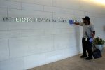 A facilities maintenance staff member cleans signage at the International Monetary Fund headquarters building in Washington DC (Photo: Reuters/Yuri Gripas).