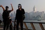 Masked anti-government protesters react in front of the skyline during a protest at Tsim Sha Tsui in Hong Kong, 27 October 2019, (Photo: Tyrone Siu/ Reuters).