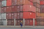 A worker cycles past containers outside a logistics center near Tianjin Port, in northern China (Photo: REUTERS/Jason Lee).