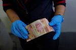 An employee wears synthetic gloves as she counts Indonesia's rupiah banknotes amid the spread of coronavirus disease (COVID-19) in Jakarta, Indonesia, 19 March 2020 (Photo: REUTERS/Willy Kurniawan).