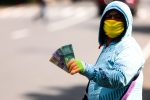 A currency exchange service vendor wearing a protective face mask while waiting for consumers on the sidewalk in Bandung, Indonesia, 22 May 2020. (Photo: Agvi Firdaus/INA Photo Agency/Sipa via Reuters).