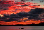 A Fijian family board their canoe as a sunset lights up the sky behind an island's mountain range in Suva 28 April, 2004 (Photo: Reuters/Gray).