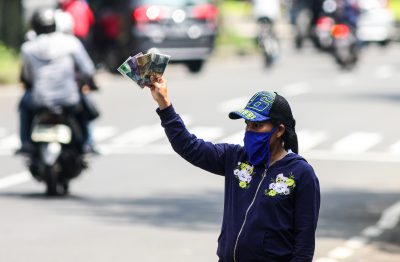 A currency exchange service vendor wearing a protective face mask while waiting for consumers on the sidewalk in Bandung, Indonesia, 22 May, 2020 (Photo: Reuters/Agvi Firdaus).