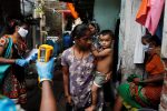 A healthcare worker checks the temperature of residents of a slum area using an electronic thermometer during a check-up campaign for the coronavirus disease (COVID-19), in Mumbai, India, 6 July 2020. (Photo: Reuters/Francis Mascarenhas).