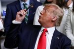 US President Donald Trump offers up a pen used to sign executive orders during a ceremony in the Eisenhower Executive Office Building at the White House in Washington DC, 24 July 2020 (Photo: Reuters/Leah Millis).