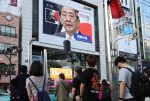 People watch a large screen which displays Prime Minister Shinzo Abe's press conference as he will resign due to his deteriorating health in Tokyo, 28 August 2020 (Photo by Yoshio Tsunoda/AFLO via Reuters).