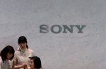 Receptionists of Sony Corp are seen in front of the company's logo at the headquarters in Tokyo, Japan, 22 May 2013.