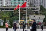 People seen in front of the Hong Kong and China flag as they line up to have their COVID-19 swab test done at a makeshift COVID-19 testing centre near a public housing estate (Photo: Sipa USA/Miguel Candela).