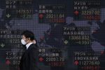 A man wearing a face mask walks past an electronic board showing currency exchange rates at a securities firm in Tokyo, March 2021 (Photo: James Matsumoto/SOPA Images/Sipa USA via Reuters)
