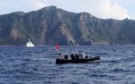 A Japan Coast Guard boat and vessel sail past one of the disputed Senkaku/Diaoyu islands, 18 August 2013 (Photo: Reuters/Ruairidh Villar).