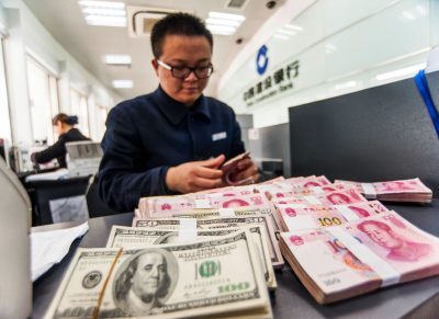 A Chinese bank clerk counts renminbi yuan and US dollar banknotes, Nantong, China, 1 March 2016 (Photo: Reuters).