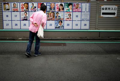 A voter watches candidate posters, including current governor Yuriko Koike, for the Tokyo Governor election in front of a voting station amid the coronavirus disease (COVID-19) outbreak, in Tokyo, Japan, 5 July 2020 (Photo: Reuters/Issei Kato).