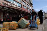 Men move bags of goods for export in front of a trading centre that houses shops and offices with Russian goods and services, in Beijing, China, 1 April 2022 (Photo: Reuters/Tingshu Wang)