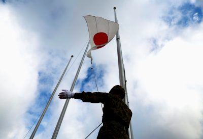 یکی از اعضای نیروی زمینی دفاع از خود ژاپن (JGSDF) پرچم ملی ژاپن را صبح در کمپ JGSDF در جزیره میاکو، استان اوکیناوا، ژاپن، 21 آوریل 2022 برافراشته است (عکس: رویترز/ایسی کاتو).