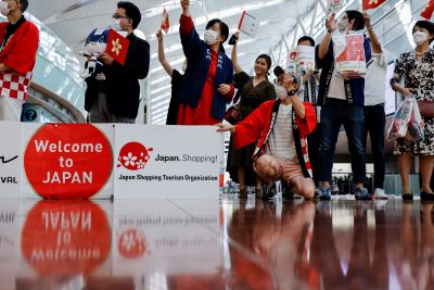 Members from Japan's shopping and tourism companies greet a group of tourists from Hong Kong upon their arrival at Haneda airport, as Japan gradually opens to tourists after two years of coronavirus disease (COVID-19) restrictions, in Tokyo, Japan, 26 June 2022 (Photo: Reuters/Issei Kato).