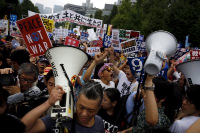 People hold placards and shout slogans as they protest against Japan's security bill outside parliament in Tokyo, 30 August 2015 (Photo: Reuters/Thomas Peter)
