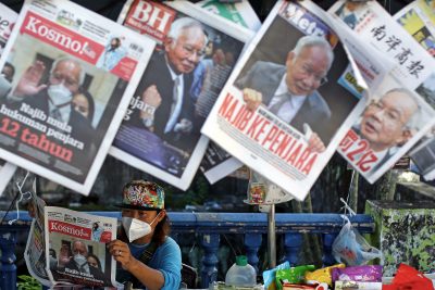 2022 年 8 月 25 日，一名供应商在阅读一份显示马来西亚前总理纳吉布拉扎克的照片和新闻的报纸（照片：路透社/Izzul Ahmad）。