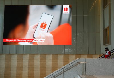 A man passes in front of a video wall showing advertisements of Shopee, the e-commerce arm of Southeast Asia's Sea Ltd, at their office in Singapore, 5 March 2021. (Photo: REUTERS/Edgar Su)