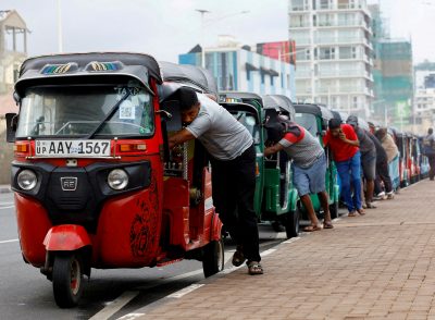 2022年7月29日、スリランカコロンボでドライバーがスリランカ経済危機の中でガソリンスタンドでガソリンを買うために並んで自動人力車を押している。  （著作権：ロイター/キム・ギョンフン）。