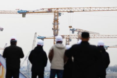 Des gens regardent près de grues debout sur un chantier de construction à Pékin, en Chine, le 12 janvier 2023 (Photo : Reuters/Tingshu Wang).