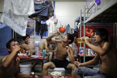 Des ouvriers migrants du bâtiment boivent de la bière pendant un repas dans leur dortoir après un quart de travail sur un chantier de construction résidentielle à Shanghai, en Chine, le 2 juillet 2013 (Photo : Reuters/Aly Song).