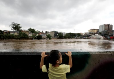 A girl looks at Ciliwung River after floods swept through Jakarta, Indonesia, 8 February 2021. (Photo: Reuters/Willy Kurniawan)