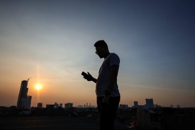 Seorang pria menggunakan ponselnya saat matahari terbenam di Jakarta, Indonesia, 11 Juni 2023 (Foto: Reuters/Willi Kurniawan).