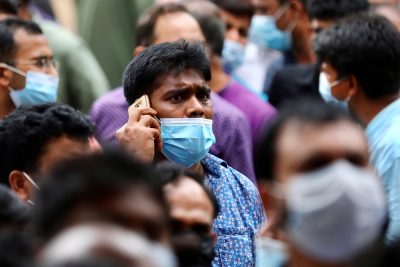 A stranded Bangladeshi worker talks over the cell phone as he waits outside of the Biman Bangladesh Airlines office, demanding flight tickets to go back to Saudi Arabia, in Dhaka, Bangladesh, 24 September 2020. (Photo: Reuters/Mohammad Ponir Hossain).