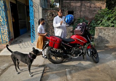 Siswa kelas V Ambika Chatterjee, 9, yang pindah dari sekolah elit ke sekolah swasta dengan biaya lebih murah, menunggu dengan mengenakan helm untuk mengantarnya, menurut ayahnya Subhash Chatterjee, 52.  di Kolkata, India, 27 April 2022 (Foto: Reuters/Rubak D Choudhury).